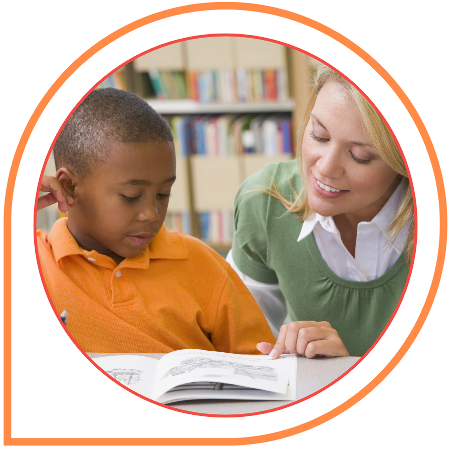 A teacher helps a young boy with a written assignment