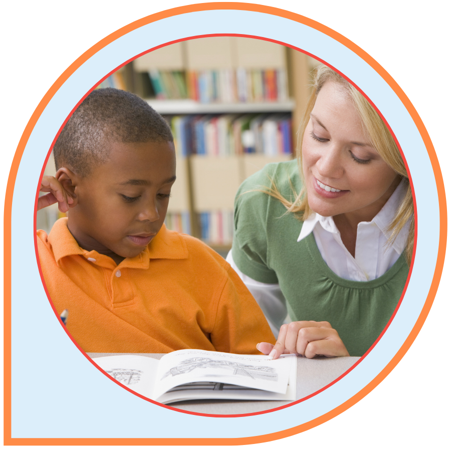 A teacher helps a young boy with a written assignment